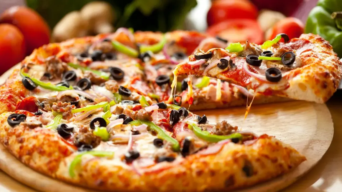 Pyszna pizza na spodzie do pizzy, z ciągnącym serem, oliwkami, papryką i salami. Idealna na spotkanie z przyjaciółmi.