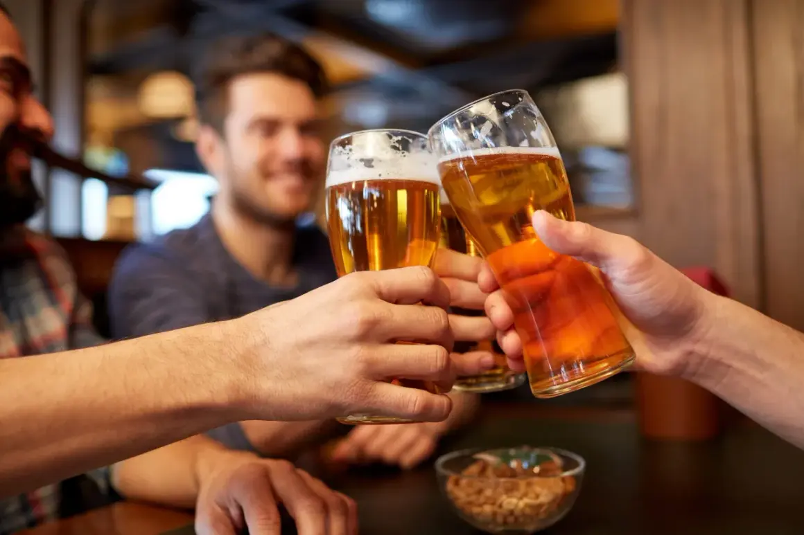 Trzech przyjaciół wznosi toasty. W rękach trzymają szklanki z bursztynowym piwem, a na stole stoi miseczka z orzeszkami. Idealny wieczór z piwem małym mocnym.