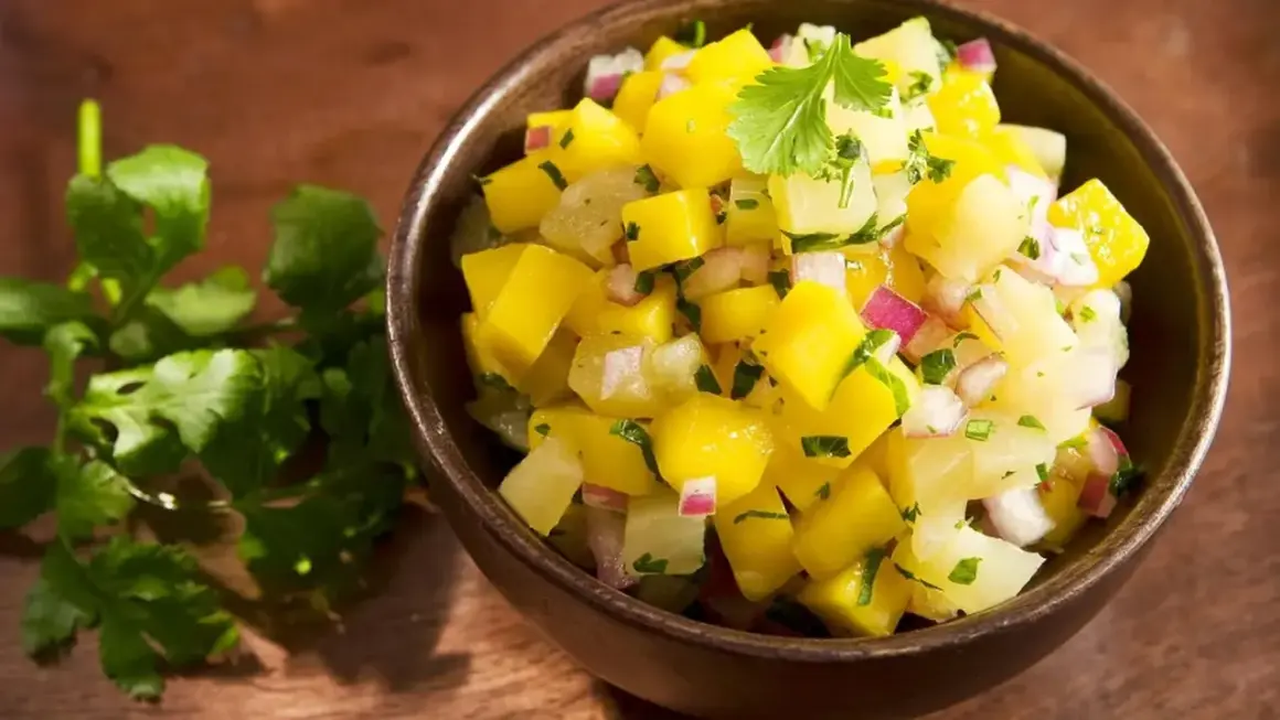 Miseczka pełna świeżej, kolorowej salsy mango z kawałkami mango, cebuli i kolendry. Idealna na letnie dni.