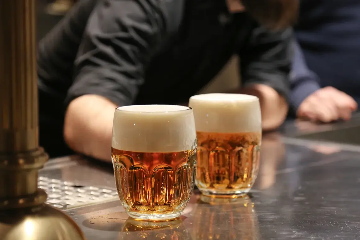 Dwa kufle pysznego czeskiego piwa z gęstą pianką stoją na barze.