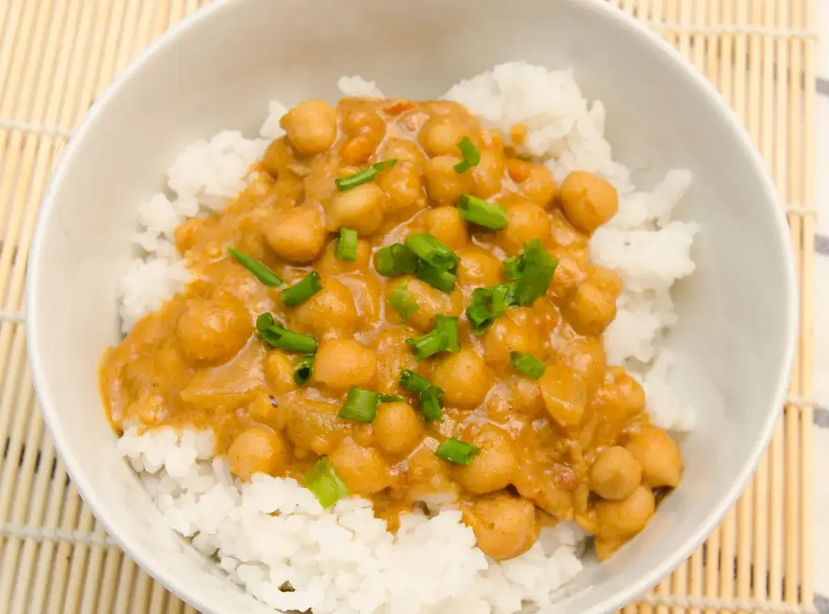 Miseczka ryżu z aromatycznym curry z cieciorki, posypana szczypiorkiem. Pyszna ciecierzyca w sosie.