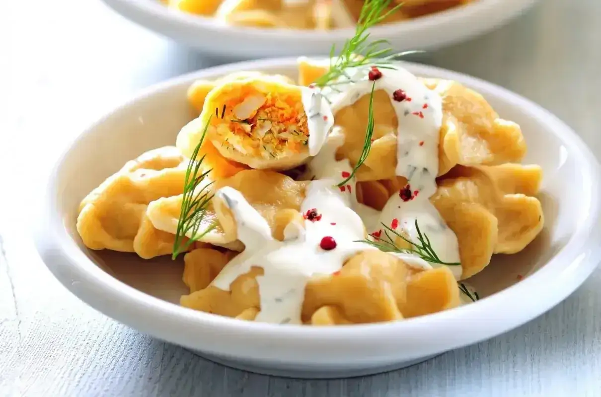 Pyszne pierogi z farszem warzywnym, polane sosem śmietanowym i posypane koperkiem. Idealne, co w piątek na obiad zamiast ryby.