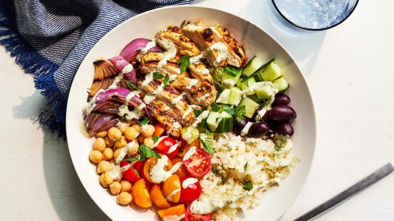 Pyszny bowl z grillowanym kurczakiem, ciecierzycą, pomidorkami, ogórkiem, oliwkami i ryżem. Idealne przepisy na lekki obiad.