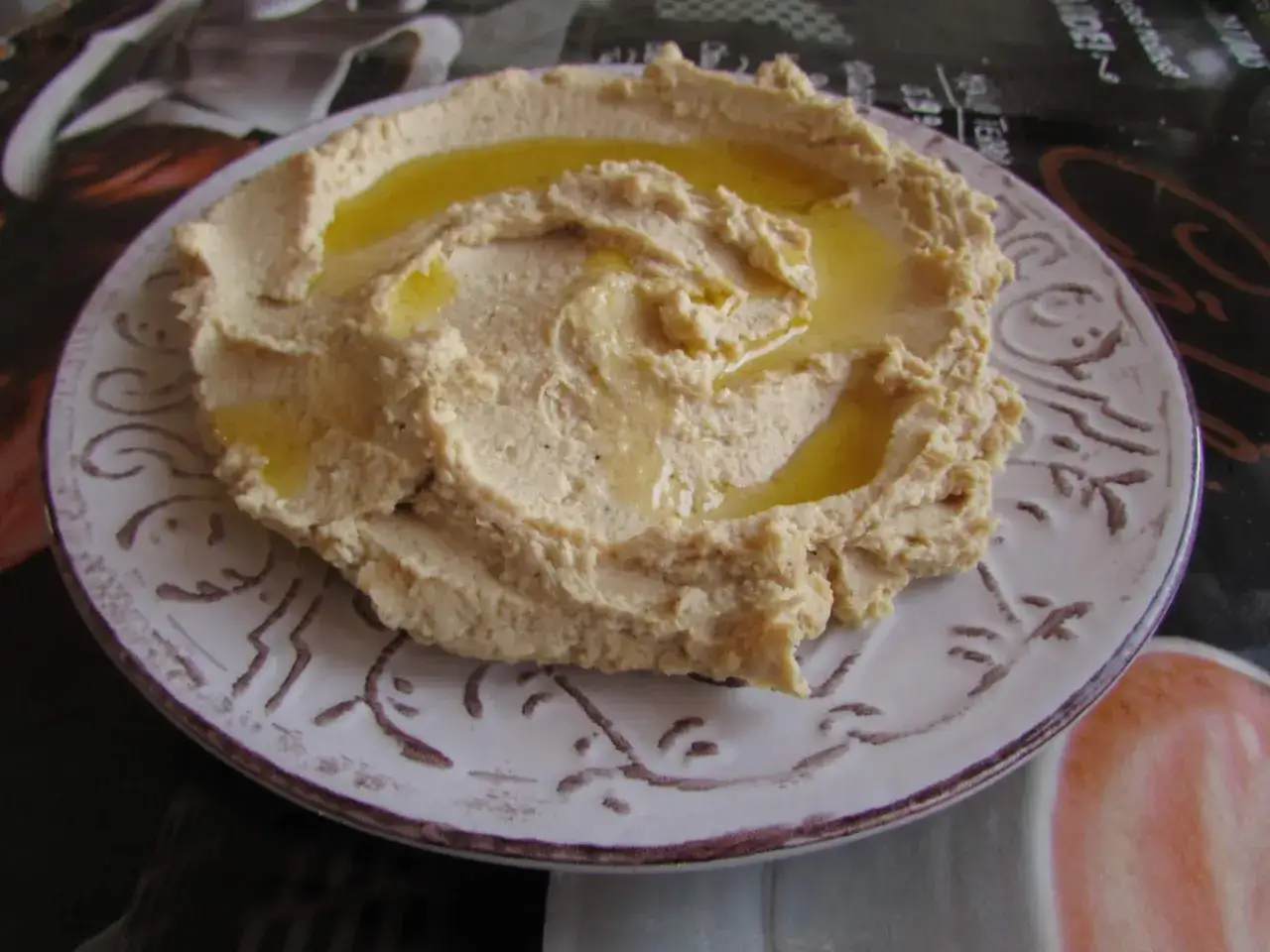 Puszysty, kremowy hummus polany oliwą, podany na ozdobnym talerzu. To pyszne danie, które warto znać!
