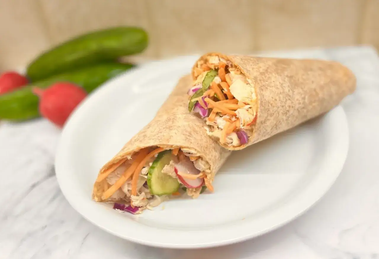 Szybka fit kolacja: pełnoziarnisty wrap z kurczakiem, chrupiącą marchewką, ogórkiem i czerwoną cebulą.