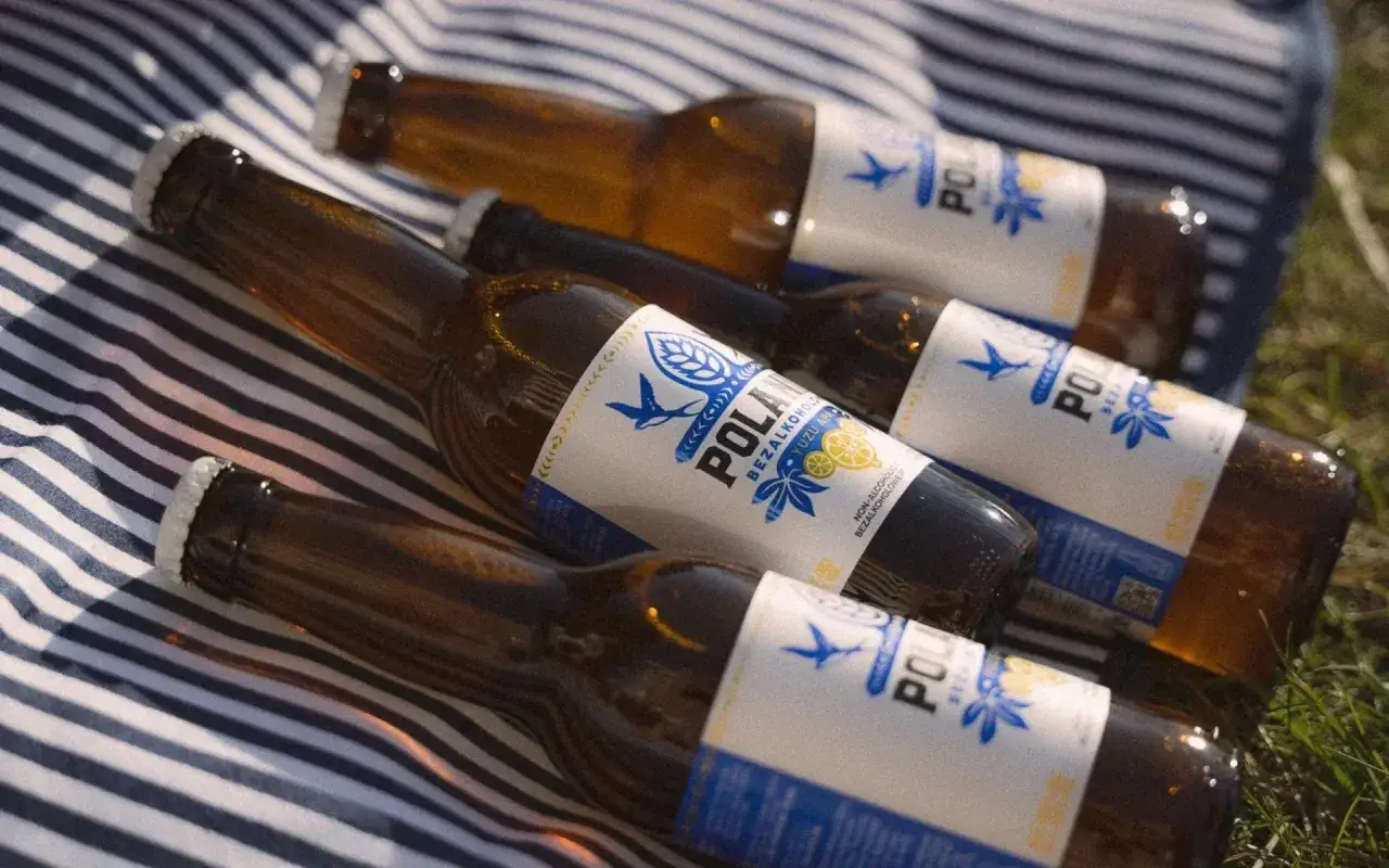 Butelki piwa bezalkoholowego na kocu. Czy piwo bezalkoholowe jest moczopędne? To pytanie może nurtować podczas pikniku.