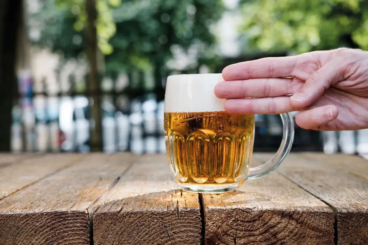 Chłodne piwo z nalewaka, z gęstą pianką, w szklanym kuflu, na drewnianym stole.