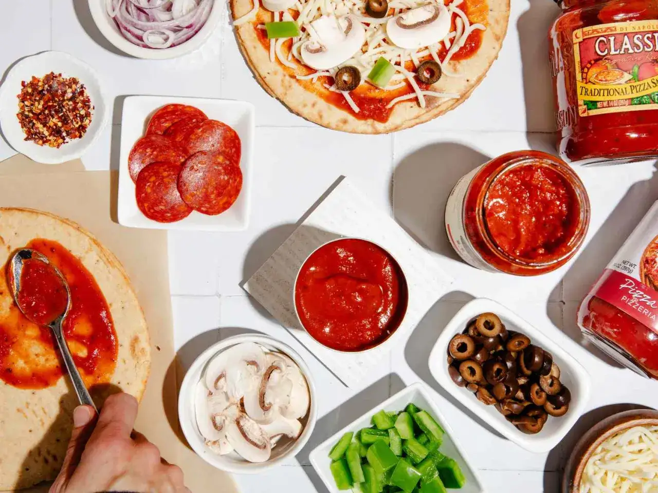 Przygotowanie pizzy: sos pomidorowy, salami, pieczarki, oliwki, papryka, cebula i ser. Czym posmarować pizzę? Sos to podstawa!