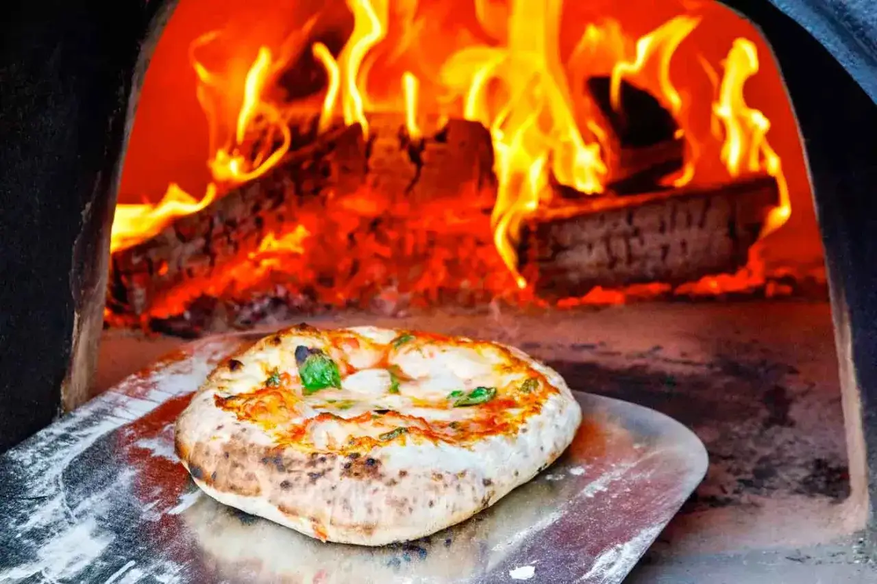 Piec opalany drewnem, płomienie i świeżo upieczona pizza na łopacie. Ciekawe ciekawostki o pizzy zaczynają się od jej przygotowania!