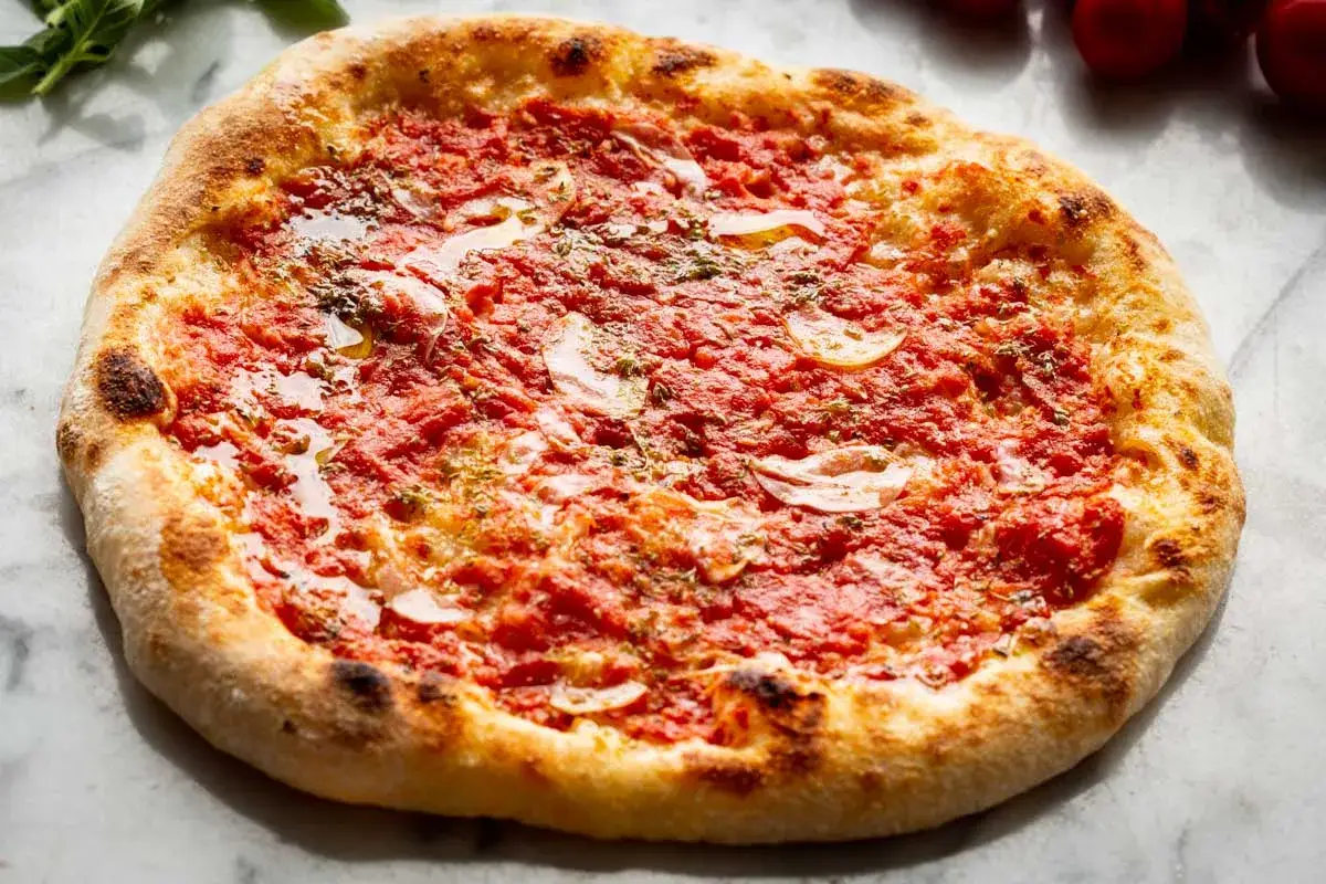 Pyszna pizza z sosem pomidorowym, plasterkami czosnku i aromatycznym oregano. Idealna na szybki obiad.