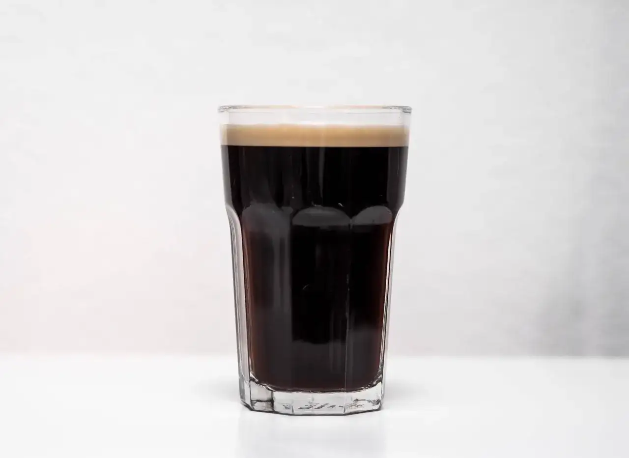Szklanka z ciemnym, gęstym piwem stout, zwieńczona kremową pianką. Idealne na chłodne wieczory.