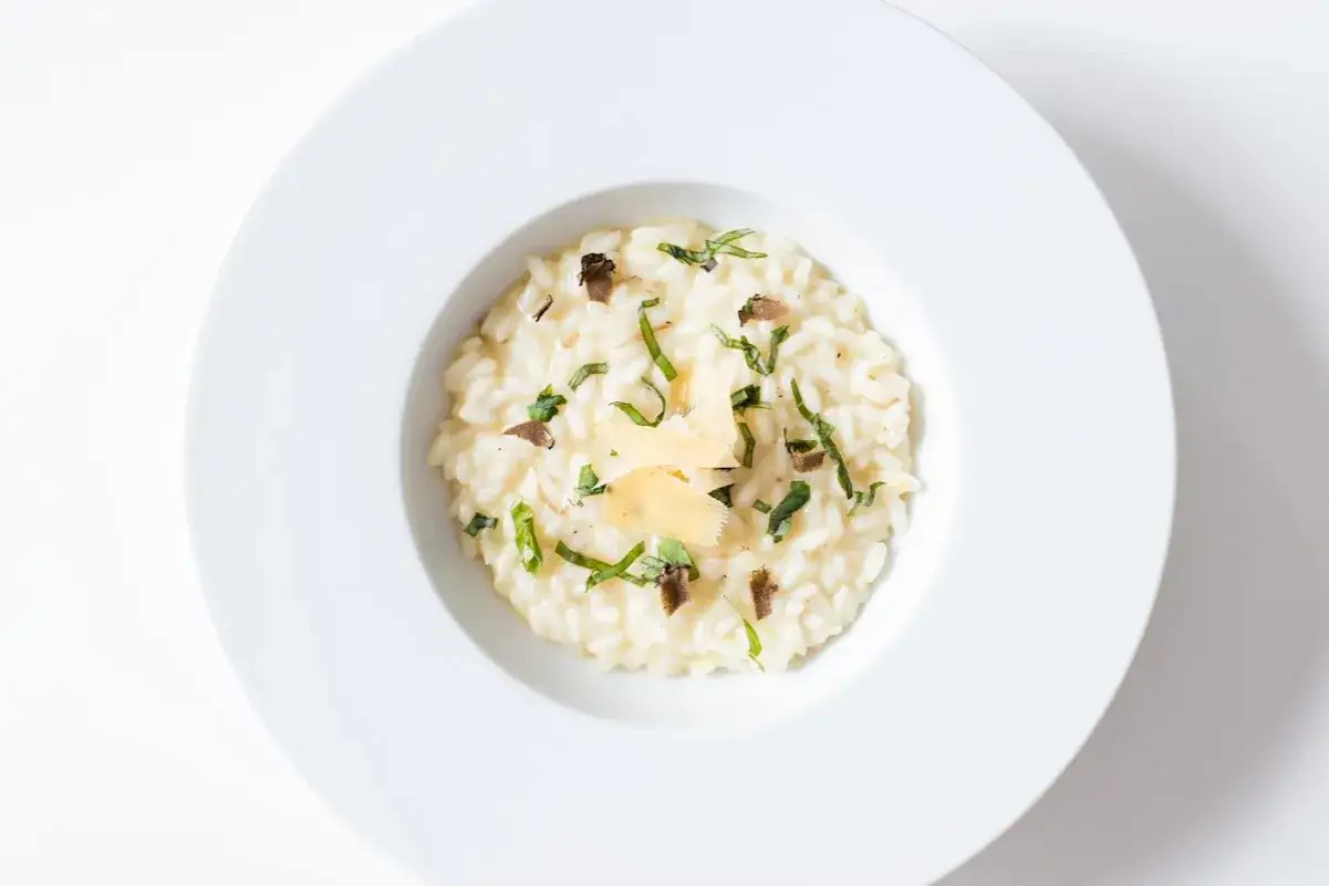 Kremowe risotto z truflami i parmezanem, jedno z wykwintnych włoskich dań głównych, podane w białej misce.