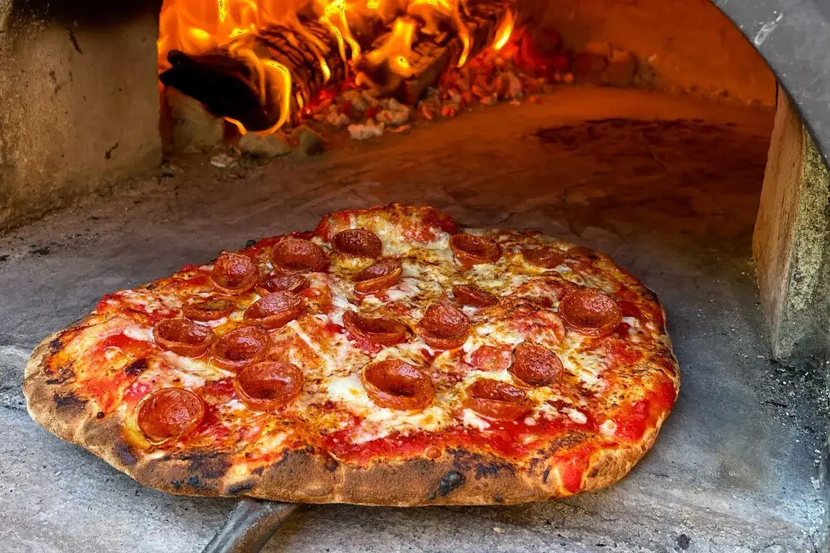 Pyszna pizza pepperoni prosto z pieca opalanego drewnem. Czy można przygotować pizzę wcześniej? Tak, ale świeżo upieczona smakuje najlepiej!