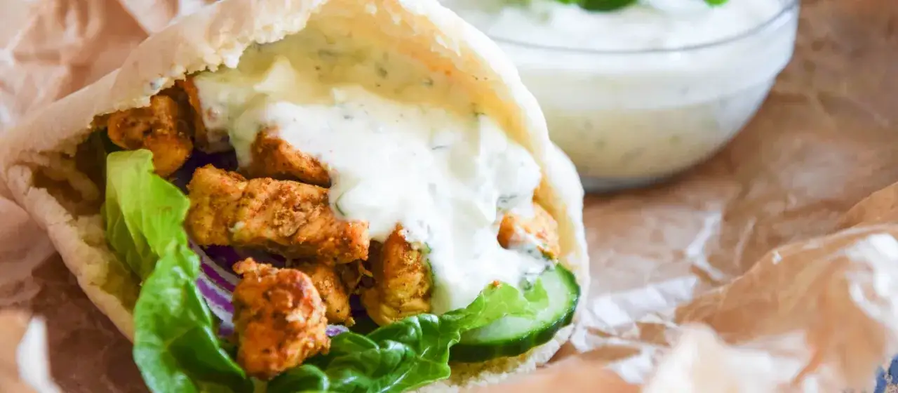 Pyszny pita gyros z soczystym kurczakiem, chrupiącą sałatą, ogórkiem i sosem jogurtowym.