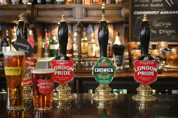 Piwo niepasteryzowane w pubie. Dwa kufle London Pride i jeden Frontier, obok kraniki z piwem.