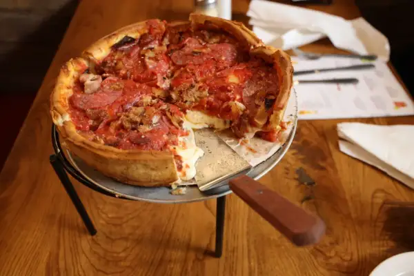 Gruba pizza z ciągnącym się serem i pepperoni, gotowa do podania.