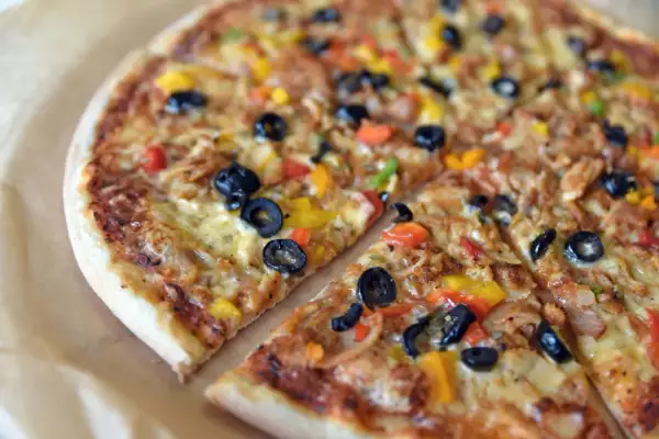 Kolorowa pizza z oliwkami i papryką, jakby prosto z podróży po pizze świata.