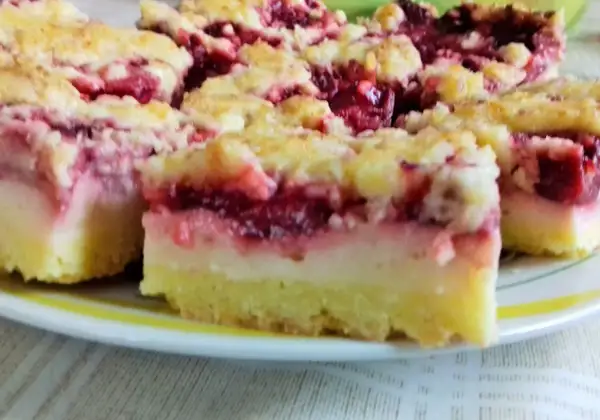Kruche ciasto z budyniem i owocami wiśni, posypane kruszonką. Pyszny deser na talerzu.