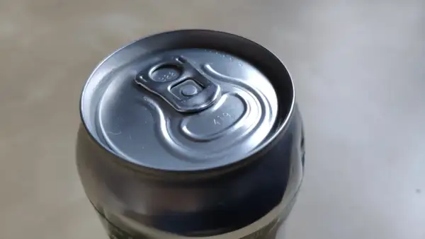 Metalowa puszka piwa z widocznymi kropkami na wieczku, które mogą oznaczać datę produkcji lub numer partii.