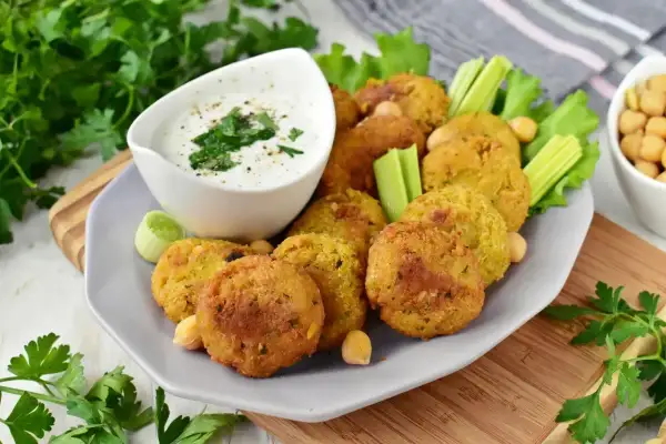 Chrupiące falafel na talerzu z sosem jogurtowym i warzywami. Idealny falafel przepis na szybką przekąskę.