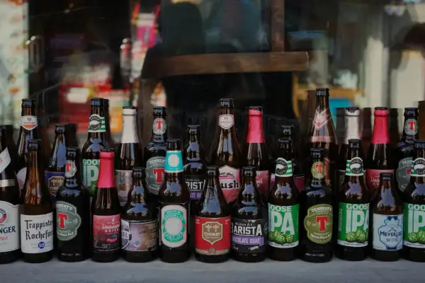 Rząd butelek po piwie, w tym Goose Island, Chimay i Lindemans. Możliwy zwrot butelek po piwie bez paragonu.