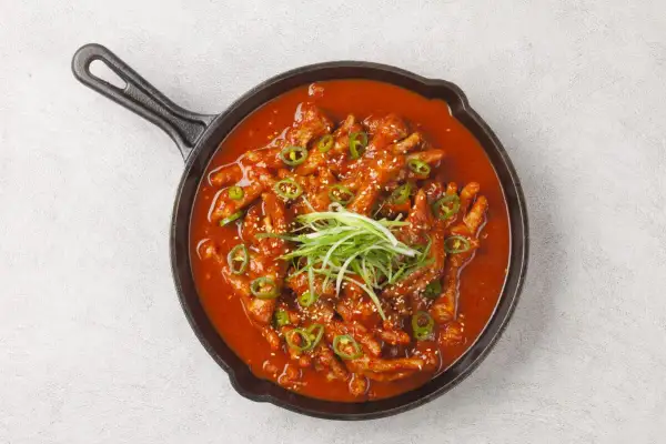 Kurczak w sosie gochujang, ozdobiony szczypiorkiem i sezamem. Idealny do dań z makaronem. Przepisy na to danie znajdziesz online.