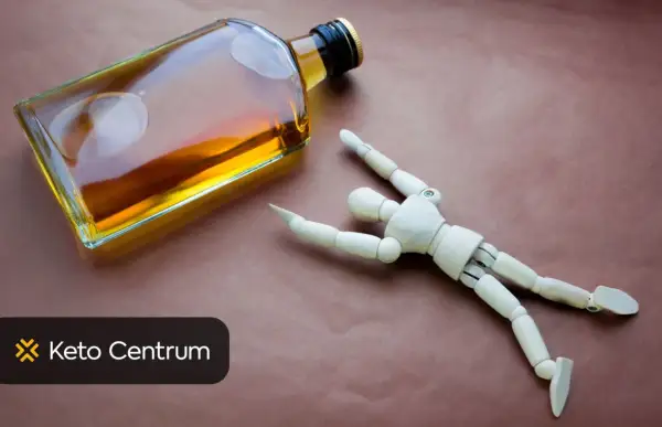 Drewniany ludzik obok butelki z alkoholem. Czy piwo wpływa na testosteron? Keto Centrum.