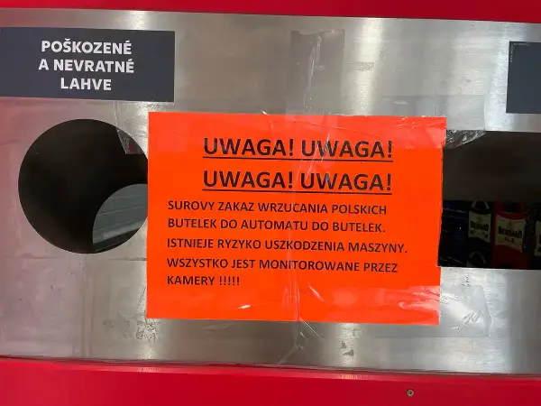 Ostrzeżenie przed wrzucaniem uszkodzonych butelek po piwie do automatu. Maszyna jest monitorowana przez kamery.