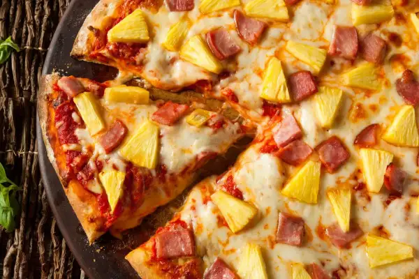 Pyszna pizza z ananasem i szynką, z ciągnącym się serem i sosem pomidorowym. Idealna na letni wieczór.